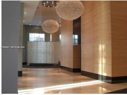A modern lobby features polished tile floors, wood-paneled walls, and large spherical crystal chandeliers — 951 Brickell Ave # 1808, Miami FL 33131, MIAMI, FL