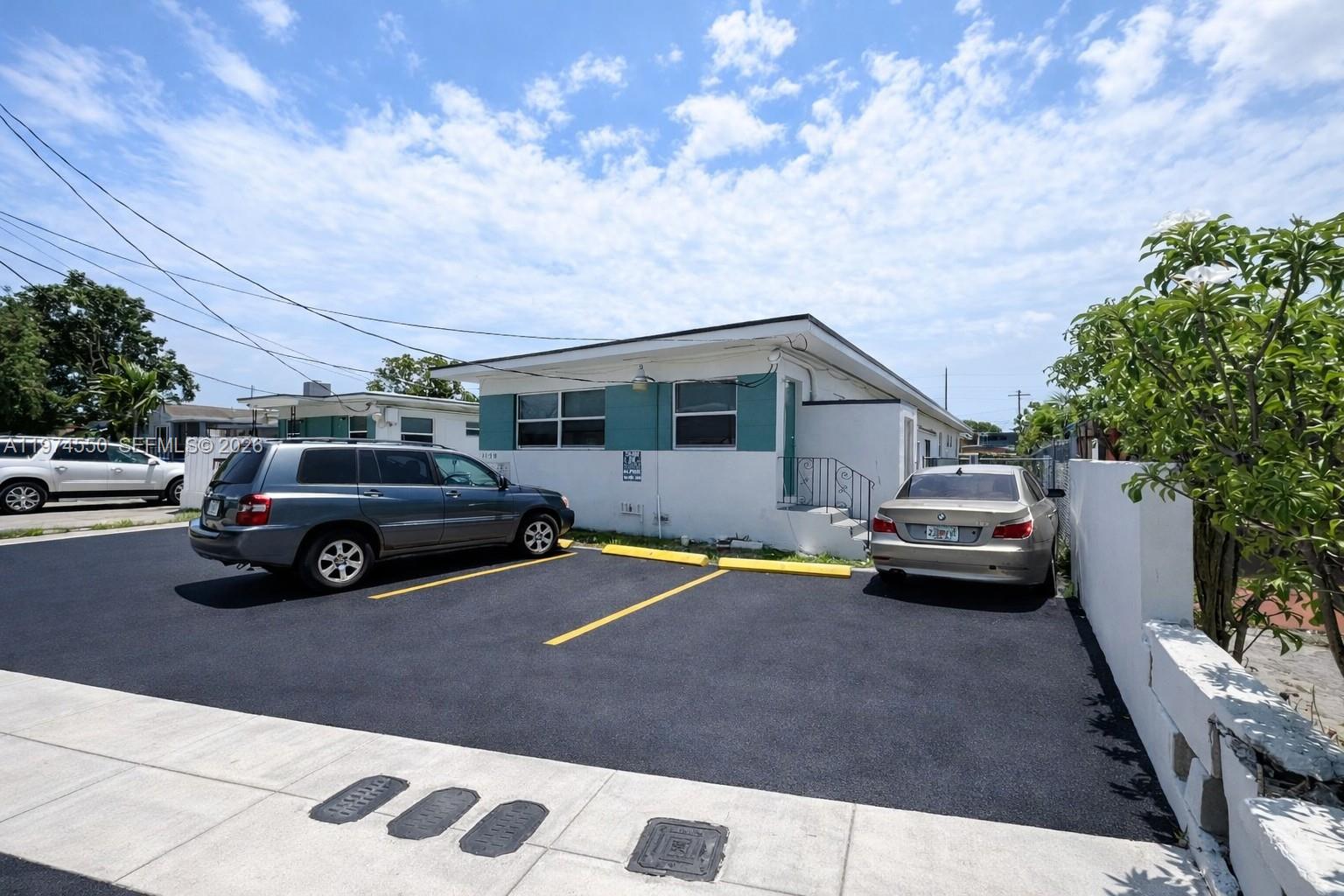 A single-story white building with a paved parking lot and two parked cars — 2150 NW 24th St, Miami FL 33142, MIAMI, FL