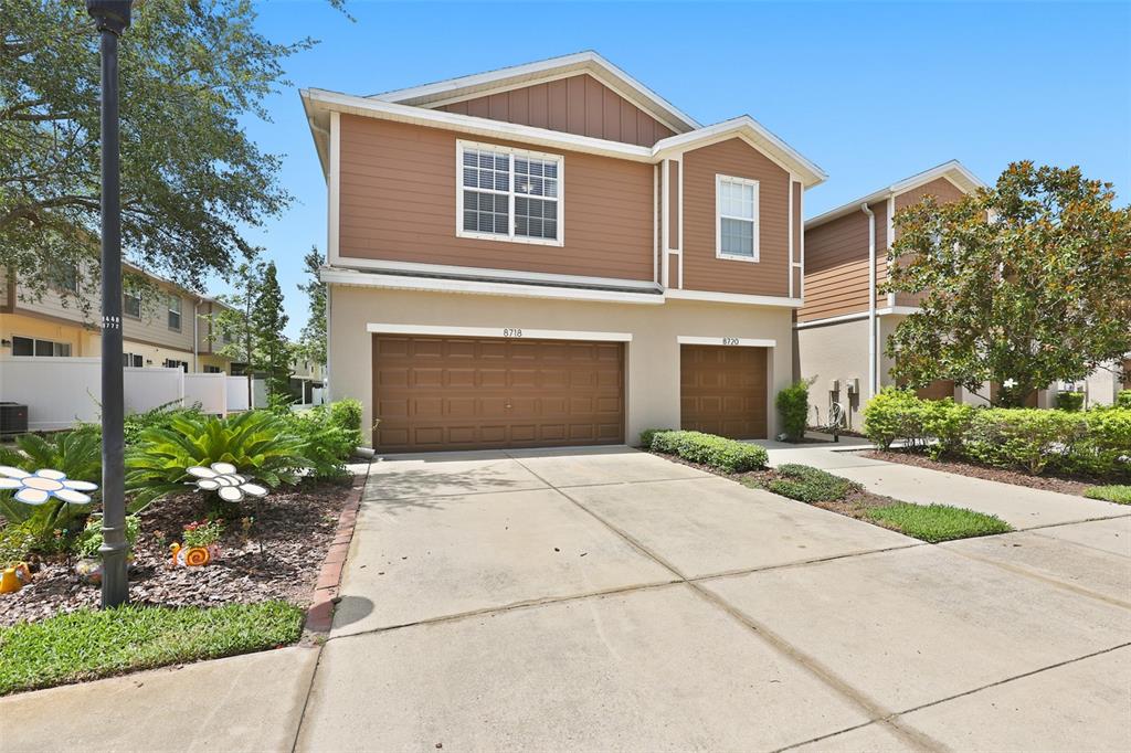 A two-story duplex house with brown siding, a two-car garage, and a concrete driveway — 8718 TURNSTONE HAVEN PLACE, TAMPA, FL