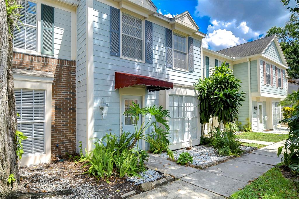 A light blue two-story townhouse with a red fabric awning over the front entrance — 13937 FLETCHERS MILL DRIVE, TAMPA, FL
