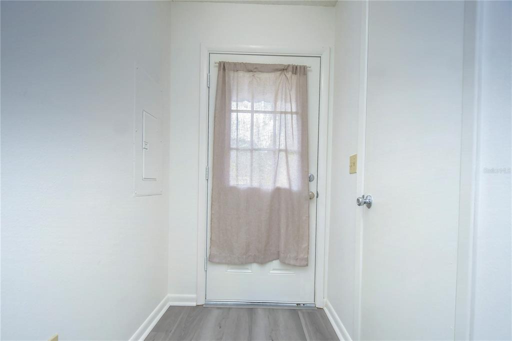 A white door with a curtain stands at the end of a small entryway — 13937 FLETCHERS MILL DRIVE, TAMPA, FL