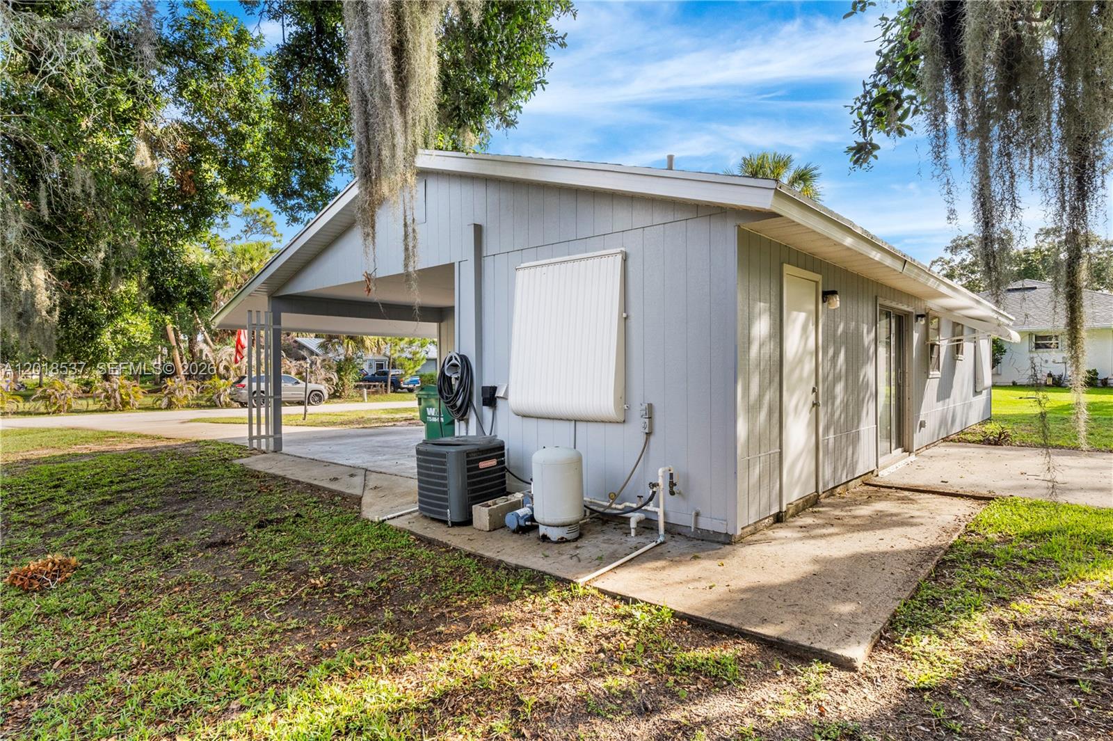 A side view of a house exterior featuring a carport, HVAC unit, and water tank — 326 Belfast, Sebastian FL 32958, SEBASTIAN, FL