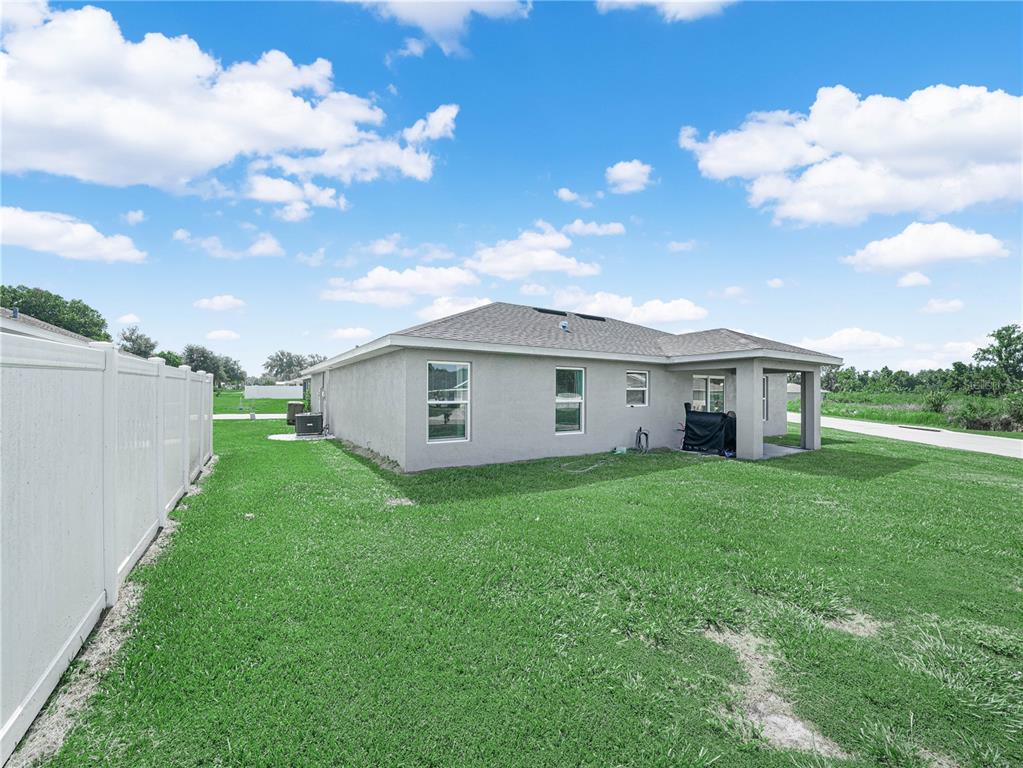 The exterior of a single-story house features a covered patio and a white vinyl fence — 346 HIDDEN CREEK, WAUCHULA, FL