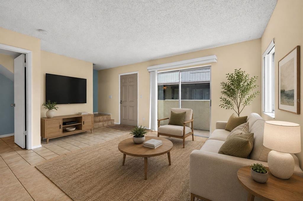 A living room features light-colored walls, tile flooring, a beige sofa, and a sliding glass door — 2943 LICHEN LANE UNIT B, CLEARWATER, FL