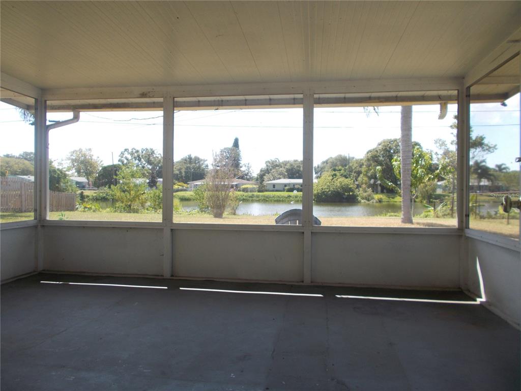 A screened-in porch with a concrete floor overlooks a backyard and a small pond — 5982 52ND AVENUE N, KENNETH CITY, FL
