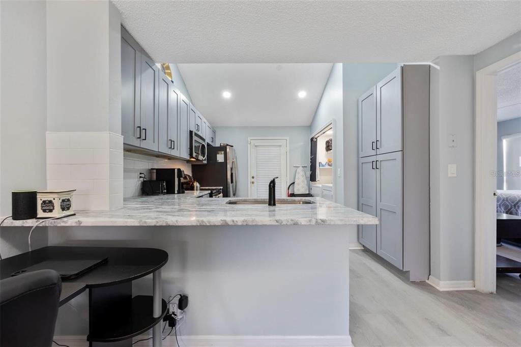 A kitchen features light blue cabinets, marble-look countertops, and a breakfast bar with a desk — 3401 CYPRESS HEAD COURT, TAMPA, FL