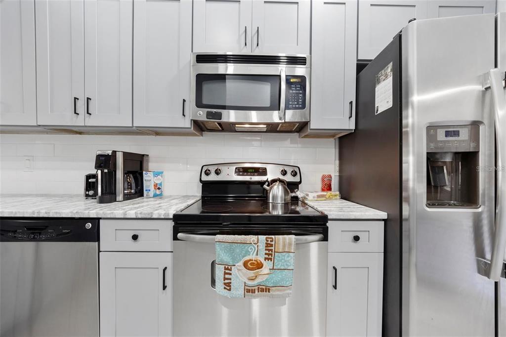 A kitchen features light gray cabinets, stainless steel appliances, and white marble-patterned countertops — 3401 CYPRESS HEAD COURT, TAMPA, FL
