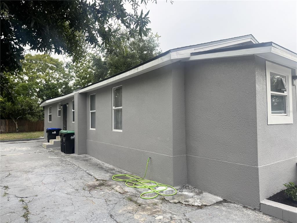 The exterior of a gray stucco house features a concrete driveway and a green hose — 425 S OBSERVATORY DRIVE, ORLANDO, FL