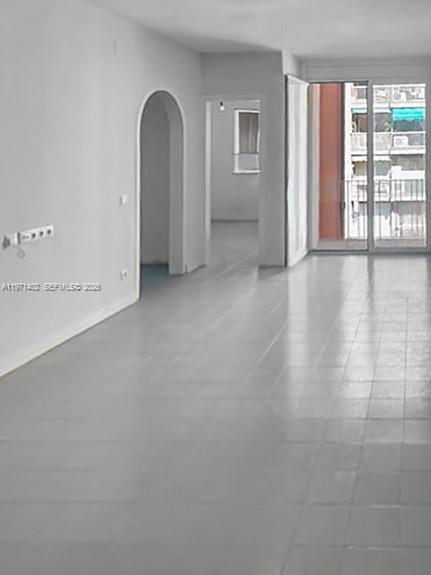 An empty living room with light-colored tile flooring, white walls, and a sliding glass door — Sant Antoni Maria Claret # 77, NJ 08025, NJ
