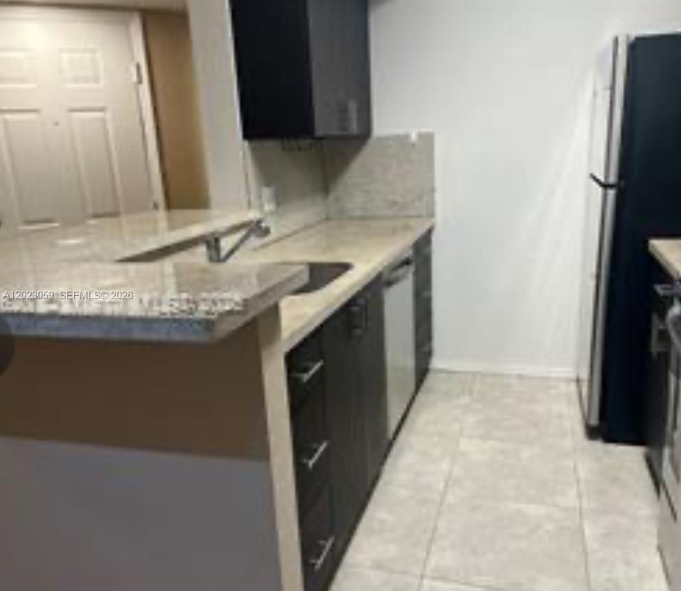 A kitchen features dark cabinets, light countertops, a sink, and a white refrigerator — 2946 S University Dr # 7110, Davie FL 33328, DAVIE, FL