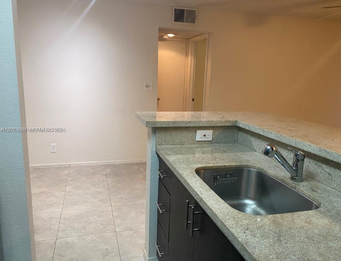 A kitchen sink with a granite countertop overlooks an adjacent tiled room — 2946 S University Dr # 7110, Davie FL 33328, DAVIE, FL