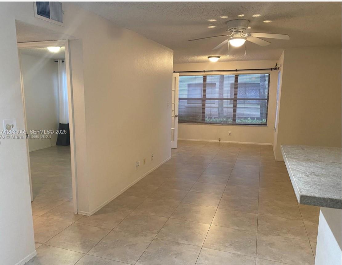 A tiled living area features a ceiling fan, large windows, and an adjacent room entrance — 2946 S University Dr # 7110, Davie FL 33328, DAVIE, FL