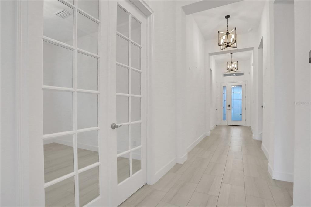 A bright hallway features white walls, light tile flooring, French doors, and two hanging lanterns — 6239 WOODHAVEN VILLAGE DRIVE, PORT ORANGE, FL