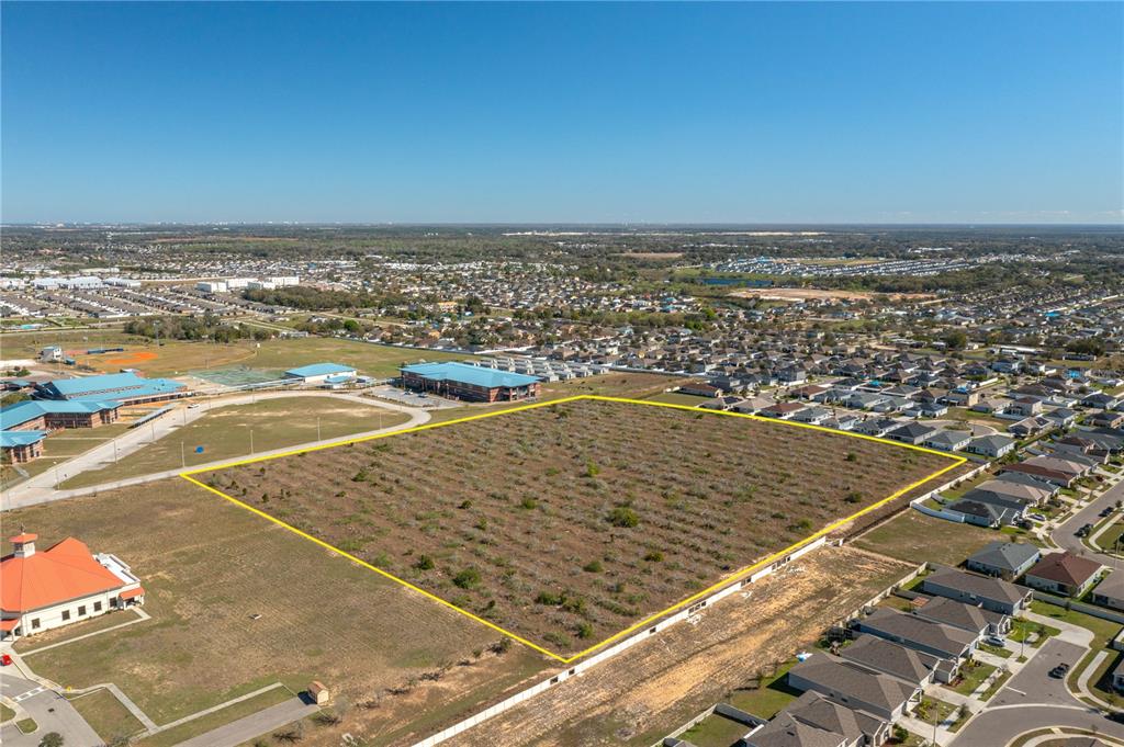 An aerial view shows a large, vacant rectangular lot outlined in yellow near residential homes — 0 ORCHID DRIVE, HAINES CITY, FL