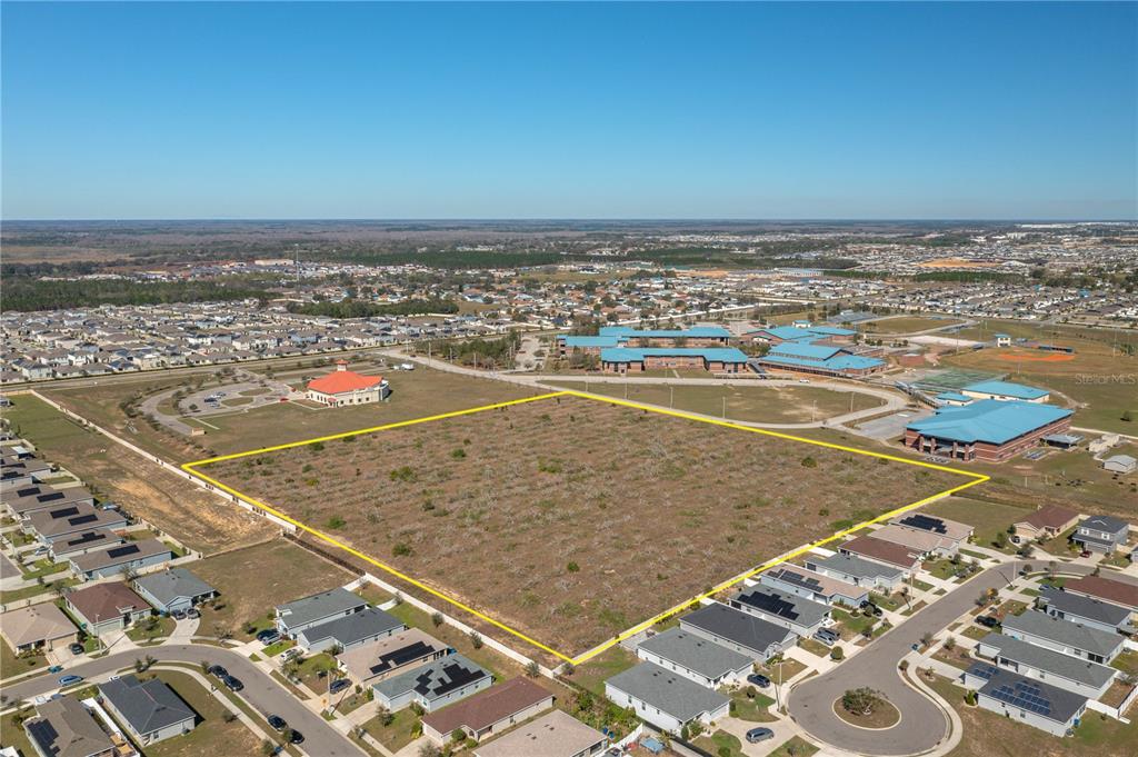 An aerial view shows a large, vacant rectangular lot outlined in yellow near residential homes — 0 ORCHID DRIVE, HAINES CITY, FL