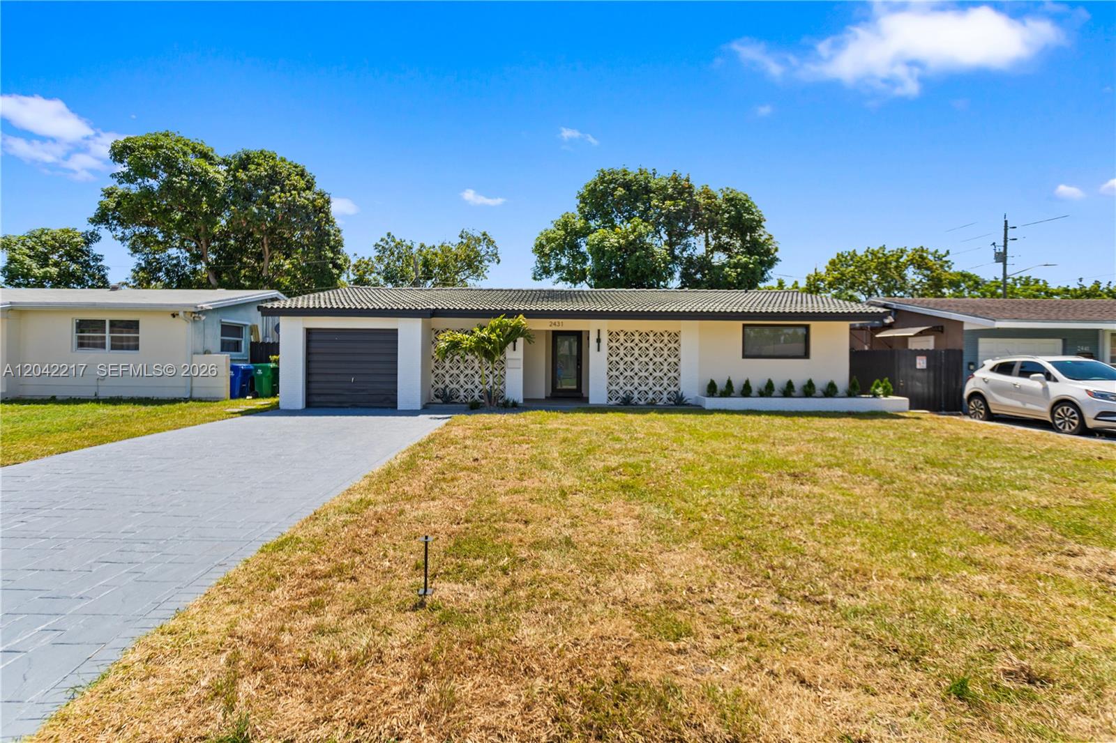 A single-story house features a gray garage door, decorative breeze blocks, and a paved driveway — 2431 Sabal Palm Dr, Miramar FL 33023, MIRAMAR, FL