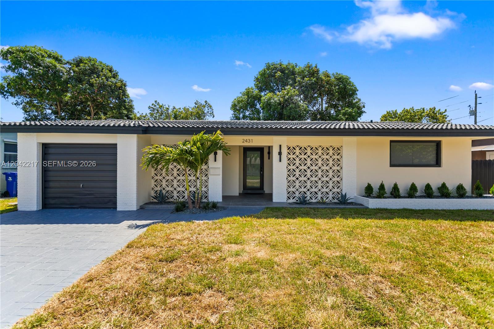 A single-story house features a gray garage, decorative breeze blocks, and a paved driveway — 2431 Sabal Palm Dr, Miramar FL 33023, MIRAMAR, FL