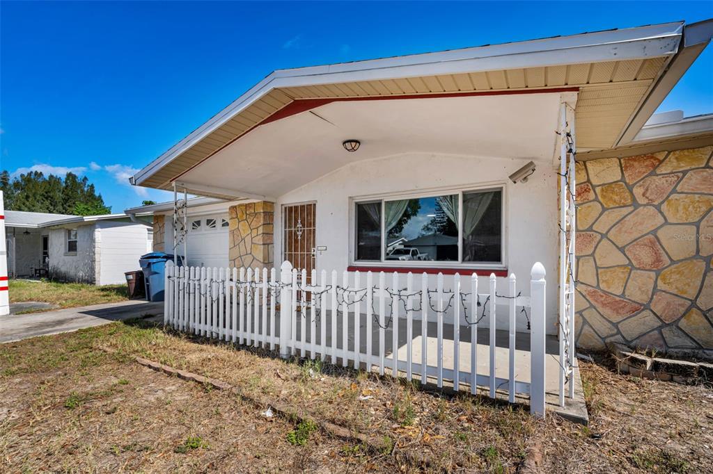 A single-story house with a stone facade, a white picket fence, and a garage — 3541 BIGELOW DRIVE, HOLIDAY, FL