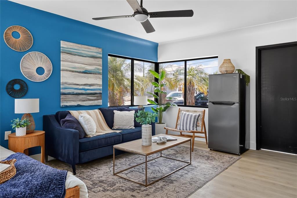A living room features a blue accent wall, a navy sofa, and a corner refrigerator — 600 COREY AVENUE, ST PETE BEACH, FL