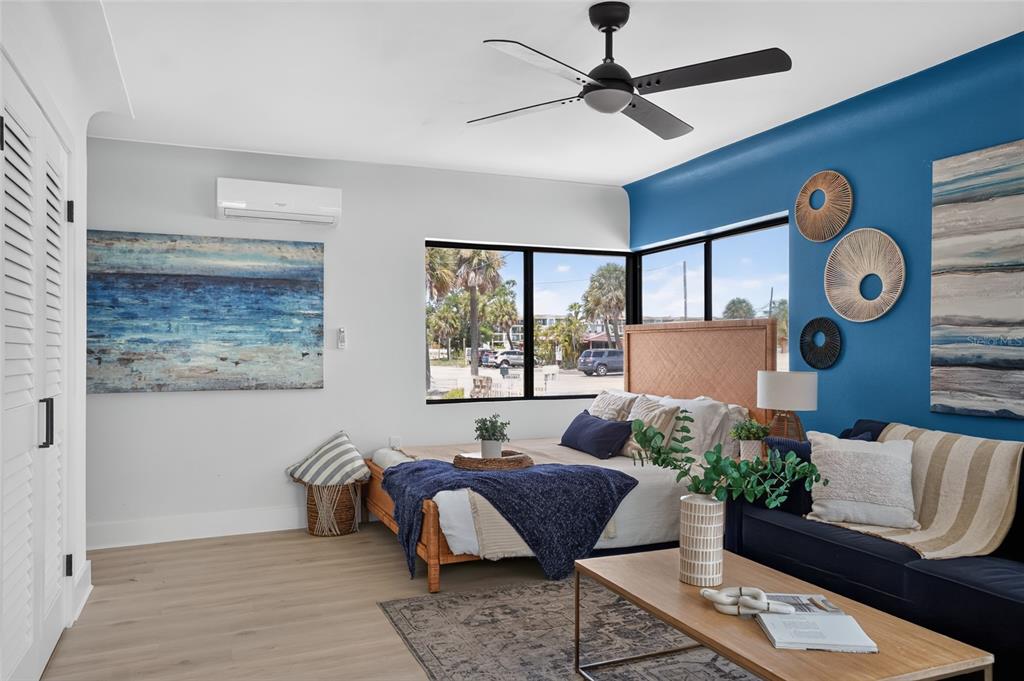 A bedroom features a blue accent wall, a ceiling fan, and a view of palm trees — 600 COREY AVENUE, ST PETE BEACH, FL