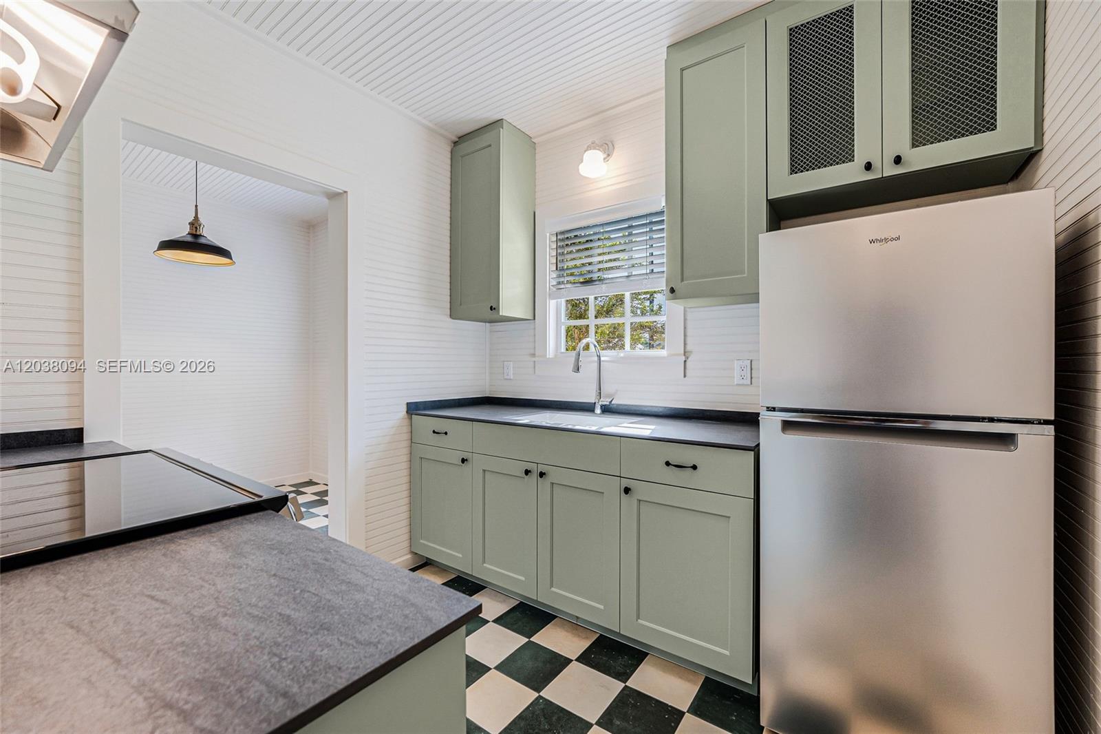 A kitchen features sage green cabinets, black countertops, and a black-and-white checkered floor — 3826 Oak Ave # 3826, Miami FL 33133, MIAMI, FL