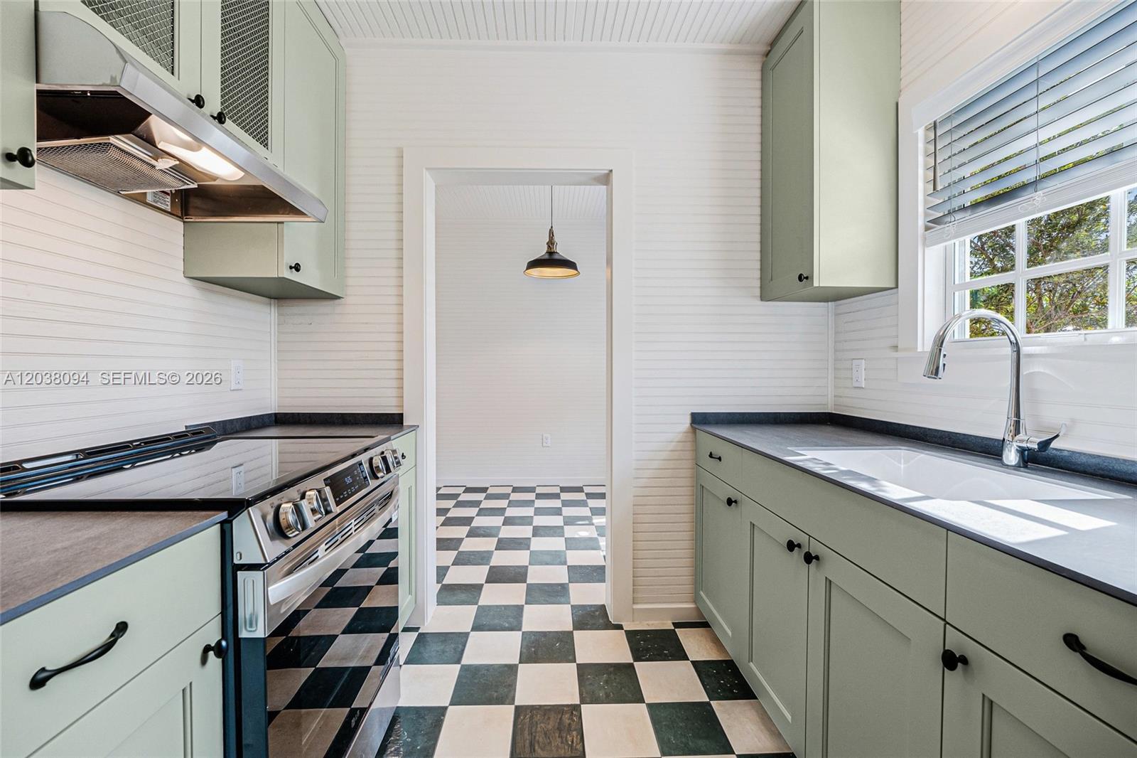 A kitchen features sage green cabinets, black countertops, and a black-and-white checkered floor — 3826 Oak Ave # 3826, Miami FL 33133, MIAMI, FL