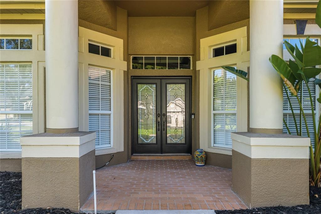 A front entryway features double glass doors, large columns, and a brick porch — 5522 REFLECTIONS BOULEVARD, LUTZ, FL
