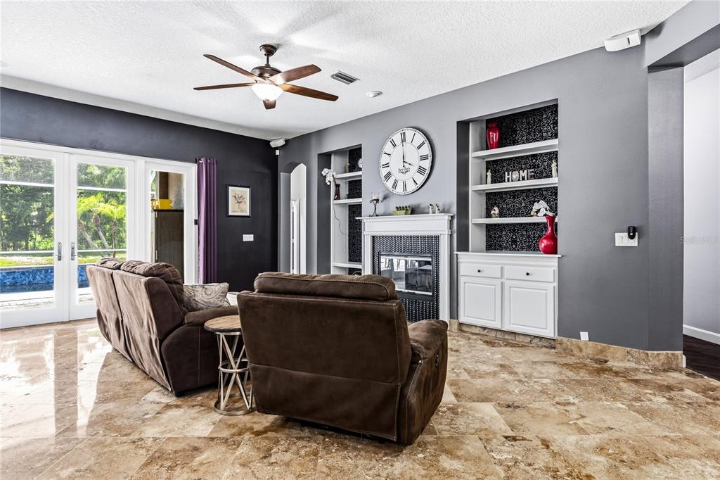 A living room features brown reclining chairs, a fireplace with built-in shelves, and tile flooring — 5522 REFLECTIONS BOULEVARD, LUTZ, FL
