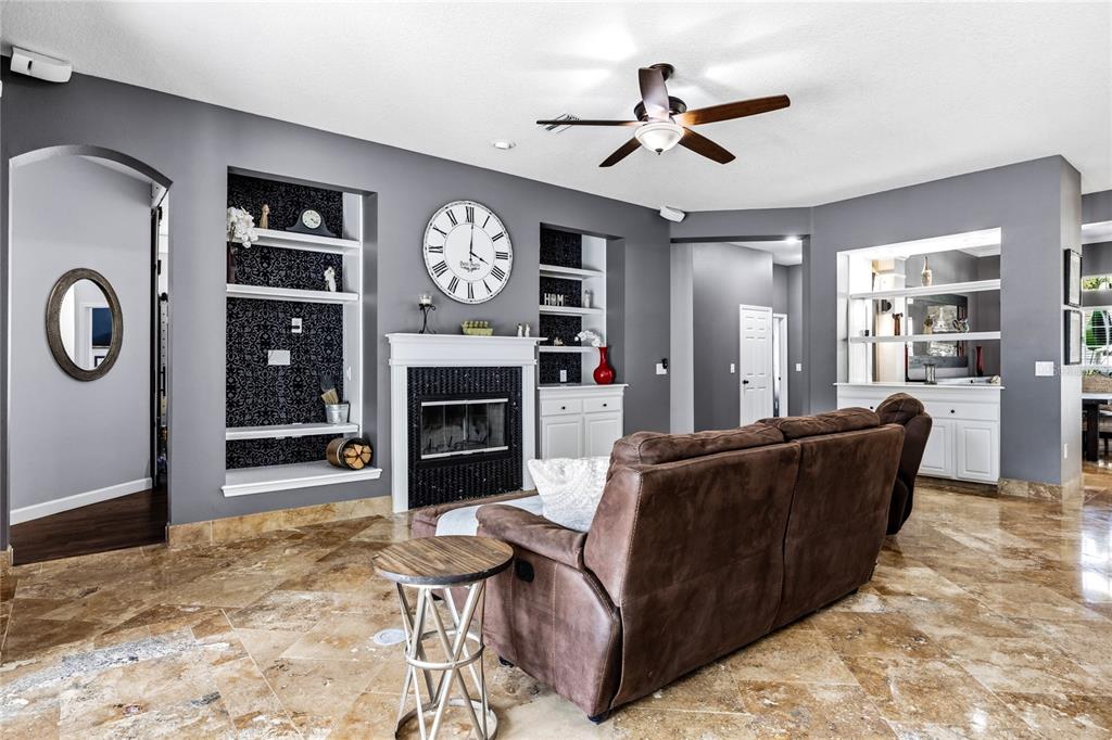 A living room features a fireplace, built-in shelving, a large wall clock, and tile flooring — 5522 REFLECTIONS BOULEVARD, LUTZ, FL