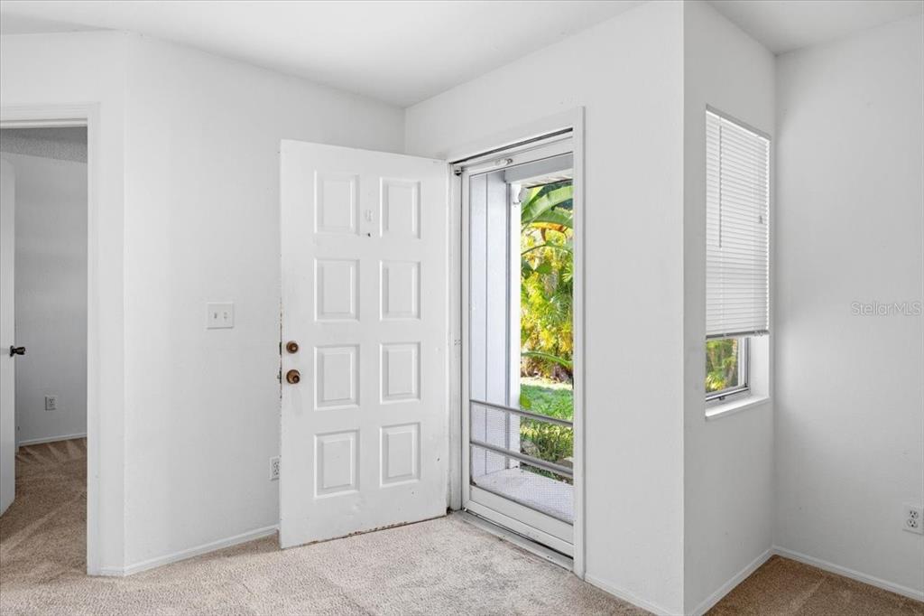 An interior view of an entryway featuring a white door, carpeted floors, and a window — 9410 TACOMA AVENUE UNIT A, ENGLEWOOD, FL