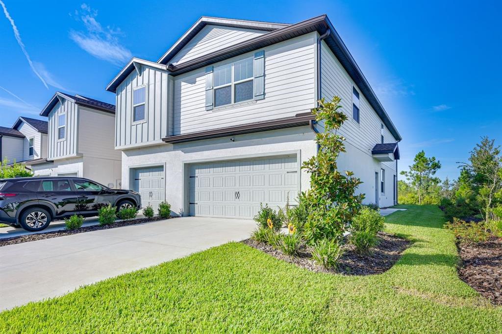A two-story house with a white exterior, a two-car garage, and a parked black SUV — 5443 ELMVIEW CROSSING, WESLEY CHAPEL, FL
