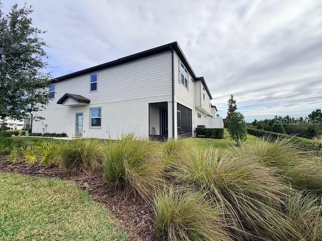A two-story white townhouse exterior features a screened-in patio and surrounding landscaping — 5443 ELMVIEW CROSSING, WESLEY CHAPEL, FL