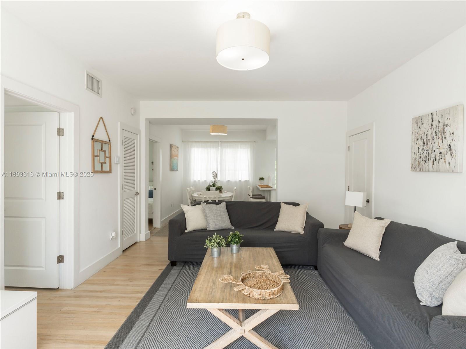 A living room with two grey sofas, a wooden coffee table, and a dining area — 241 28th St # 1, Miami Beach FL 33140, MIAMI BEACH, FL