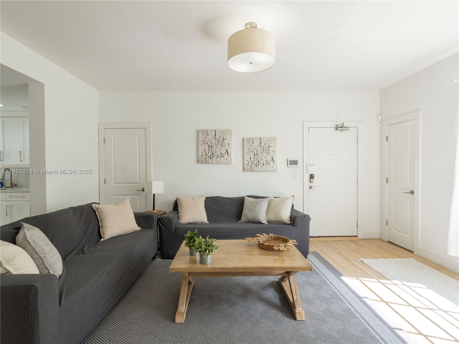 A living room features two dark gray sofas, a wooden coffee table, and a gray rug — 241 28th St # 1, Miami Beach FL 33140, MIAMI BEACH, FL