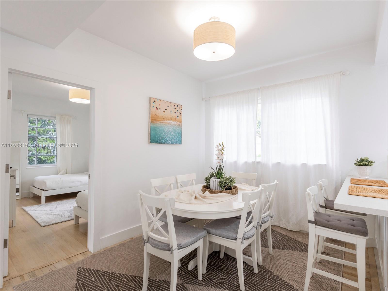 A dining area with a round white table and chairs sits adjacent to a bedroom — 241 28th St # 1, Miami Beach FL 33140, MIAMI BEACH, FL