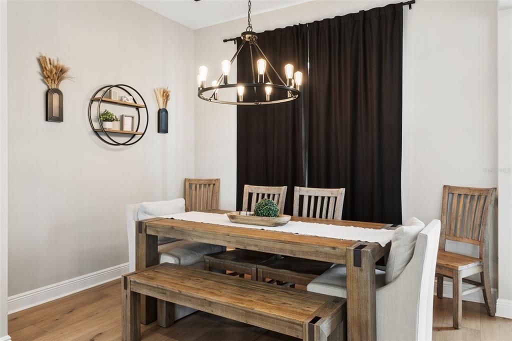 A dining room features a rustic wooden table, matching chairs, a bench, and a chandelier — 8408 WOODLEAF BOULEVARD, WESLEY CHAPEL, FL