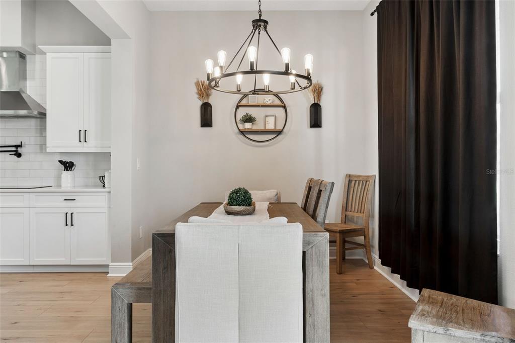 A dining area features a wooden table, upholstered chairs, a round wall shelf, and a chandelier — 8408 WOODLEAF BOULEVARD, WESLEY CHAPEL, FL
