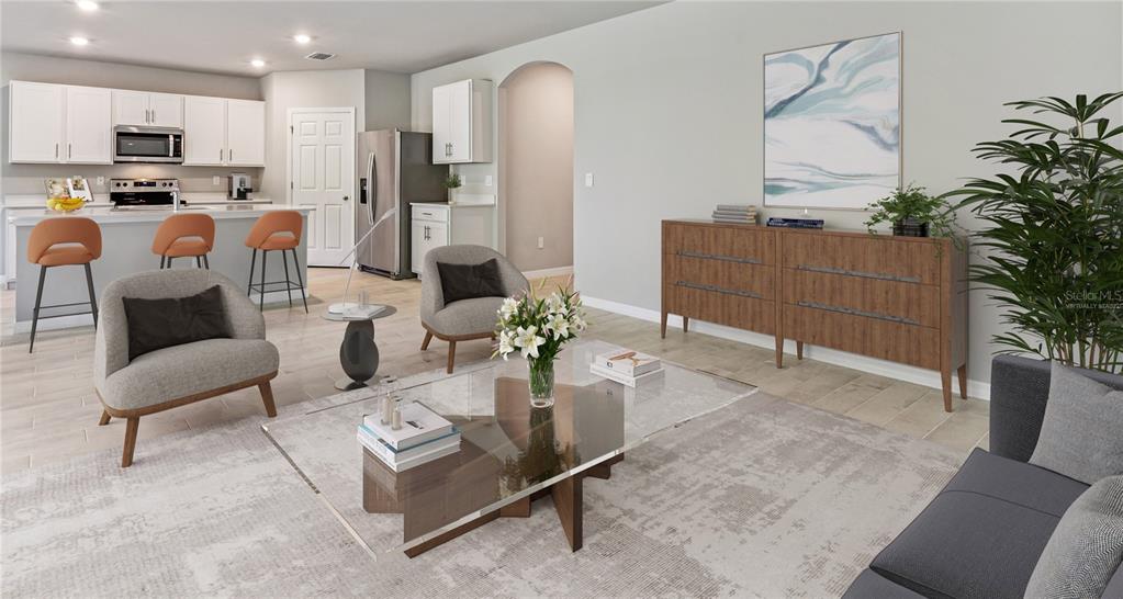 A living room with a glass coffee table, gray armchairs, and an open-concept kitchen — 25110 ALCAZAR DRIVE, PUNTA GORDA, FL