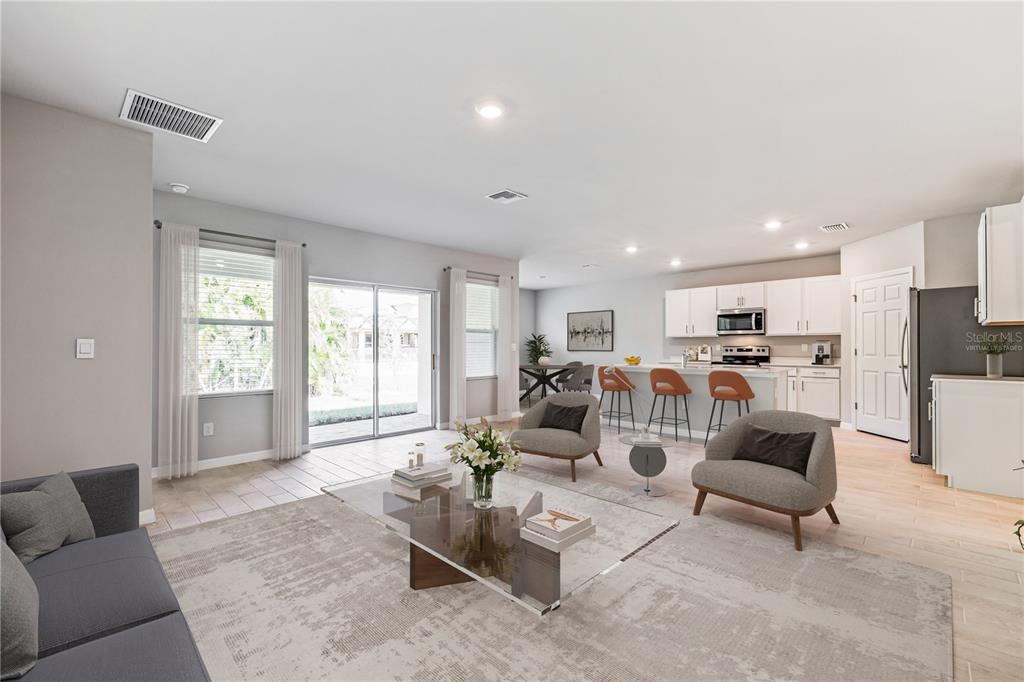 A living room with light tile floors opens to a kitchen with white cabinetry — 25110 ALCAZAR DRIVE, PUNTA GORDA, FL