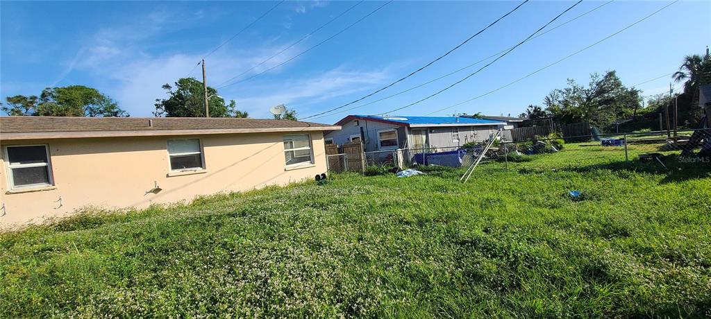 A view of the side of a tan house and a neighboring house with a blue roof — 8289 PELICAN ROAD, ENGLEWOOD, FL