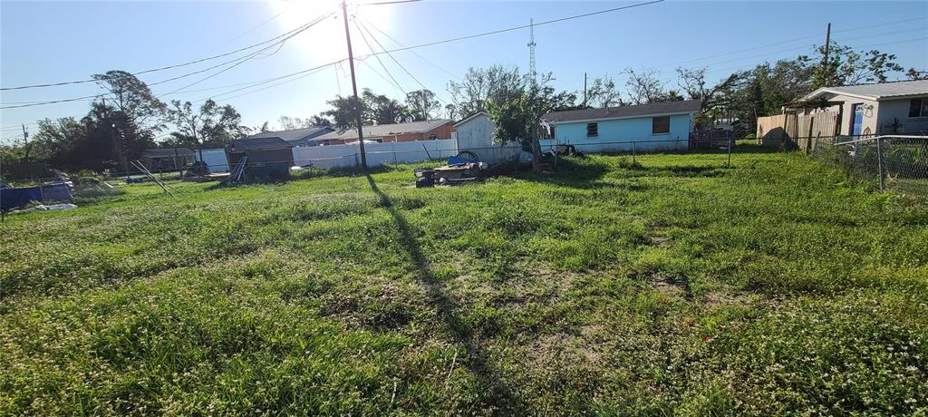 A grassy, fenced-in backyard features a small shed and a light blue house nearby — 8289 PELICAN ROAD, ENGLEWOOD, FL
