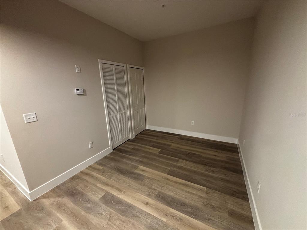 An empty room features light-colored walls, wood-look flooring, and two sets of closet doors — 4424 S TEXAS AVENUE UNIT 111, ORLANDO, FL