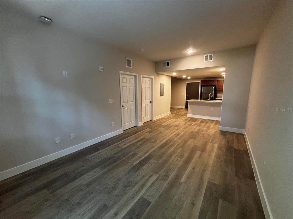 An open-concept living area with wood-look flooring leads to a kitchen with a breakfast bar — 4424 S TEXAS AVENUE UNIT 111, ORLANDO, FL