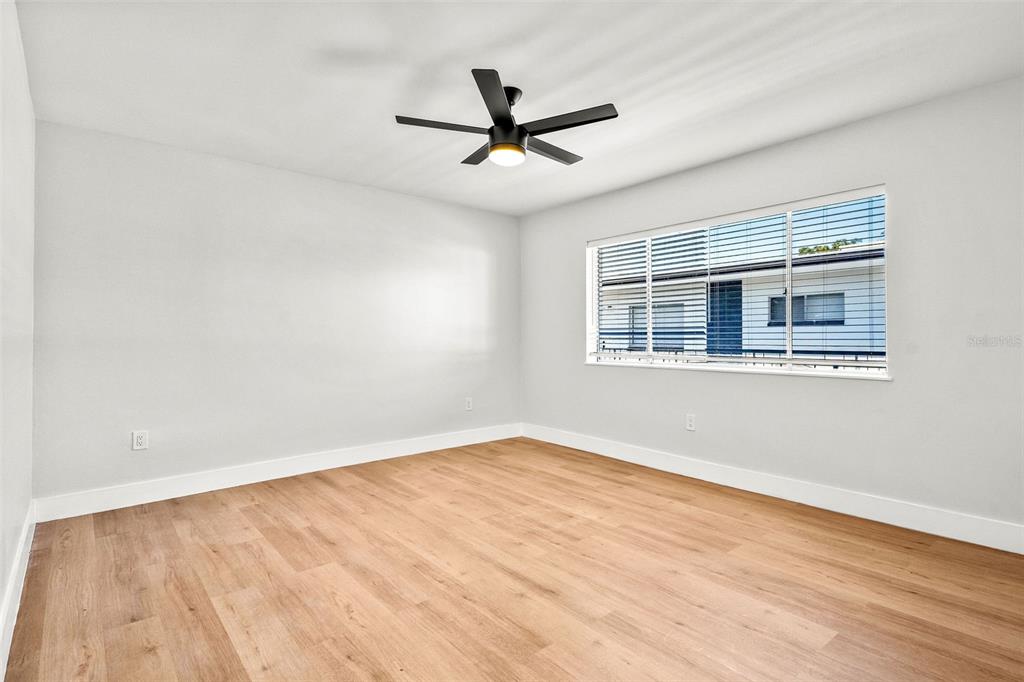 An empty room features light wood-look flooring, white walls, a ceiling fan, and a window — 300 S NIMBUS AVENUE UNIT 6, CLEARWATER, FL