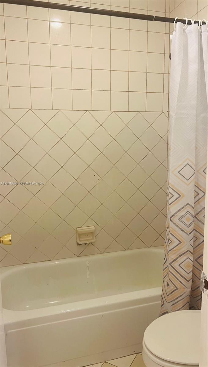A bathroom features a white bathtub, a shower curtain, and walls with square and diagonal tiles — 6505 Winfield Blvd # 53, Margate FL 33063, MARGATE, FL