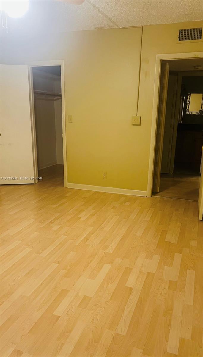 A room with light wood-look flooring, yellow walls, a closet, and an adjacent bathroom — 6505 Winfield Blvd # 53, Margate FL 33063, MARGATE, FL