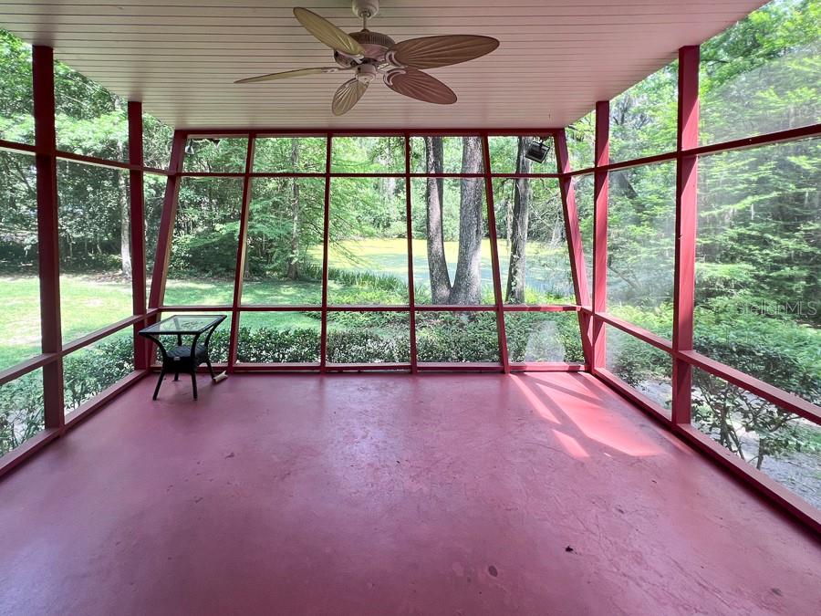 A screened-in porch with a red floor, ceiling fan, and views of a wooded yard — 411 NW 26TH STREET, GAINESVILLE, FL