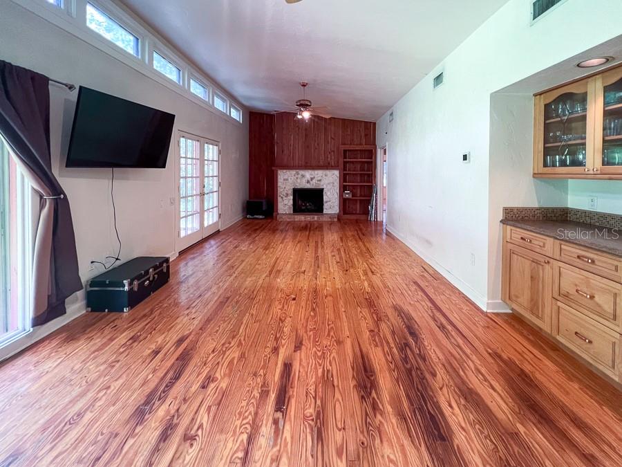 A living room with wood flooring, a stone fireplace, and a built-in wet bar — 411 NW 26TH STREET, GAINESVILLE, FL