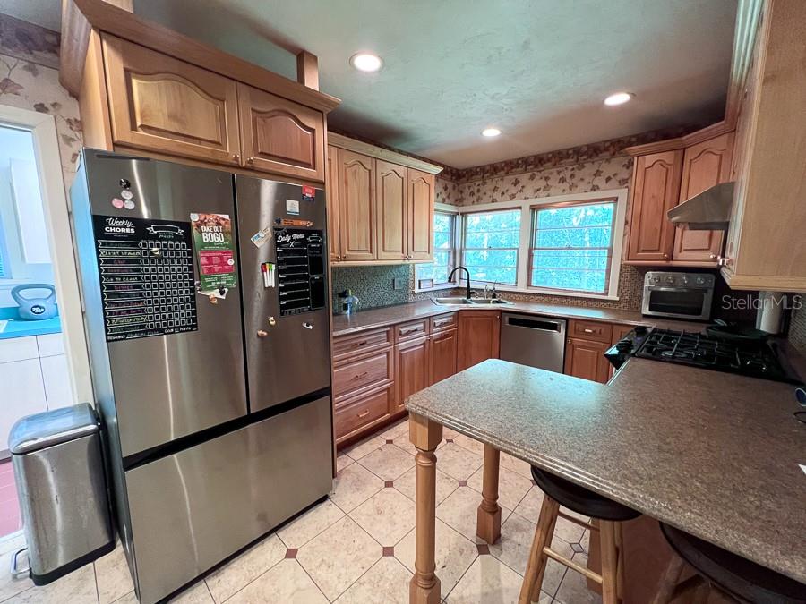 A kitchen features wood cabinets, stainless steel appliances, a peninsula, and tile flooring — 411 NW 26TH STREET, GAINESVILLE, FL