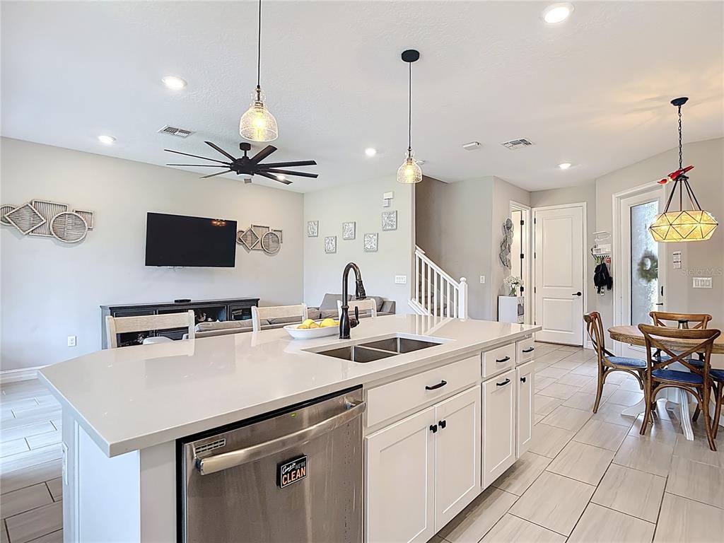 A kitchen island with a stainless steel dishwasher and sink overlooks a living area — 4868 SAN MARTINO DRIVE, WESLEY CHAPEL, FL